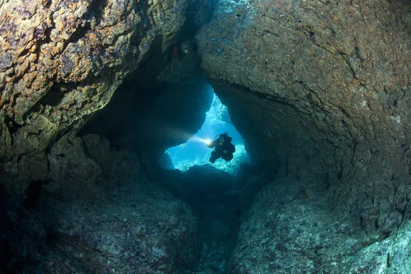 Plongeur explorant une grotte sous-marine avec une lumière artificielle