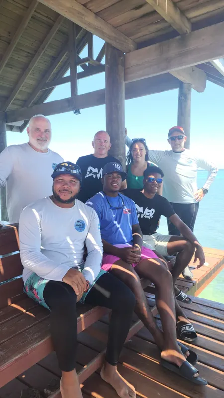 Groupe de personnes souriantes posant sur une structure en bois près de l'eau