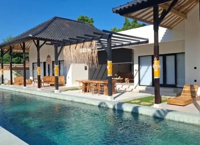 Bâtiment blanc avec piscine et mobilier en bois sous pergola