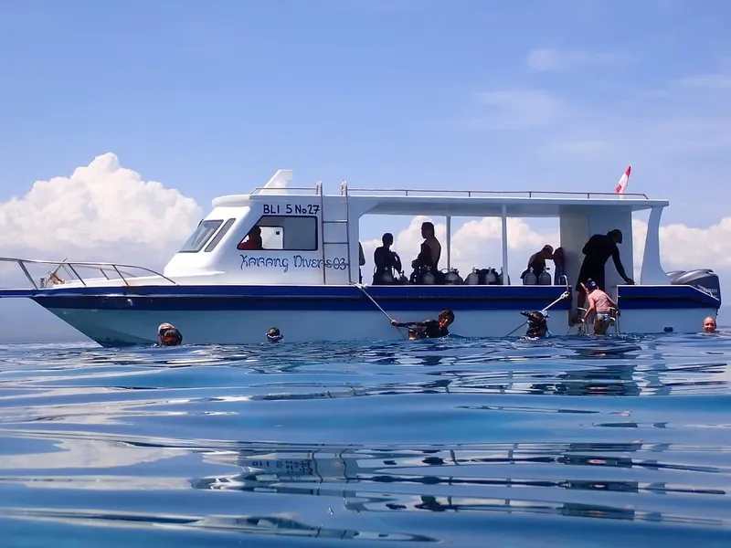 Plongeurs équipés s'apprêtent à plonger depuis un bateau blanc en mer