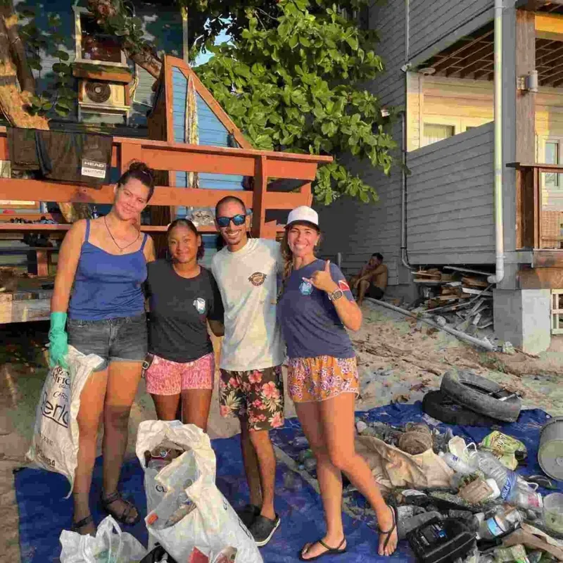 Quatre personnes souriantes posent devant une structure en bois et des déchets
