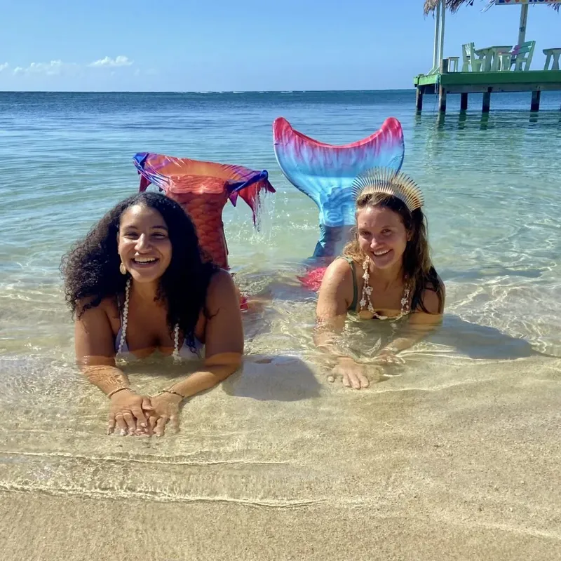 Deux femmes souriantes avec des queues de sirène dans l'eau