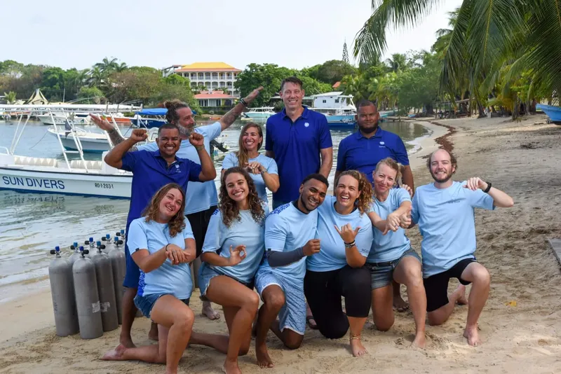 Equipe de plongee souriante posant avec des bouteilles sur une plage