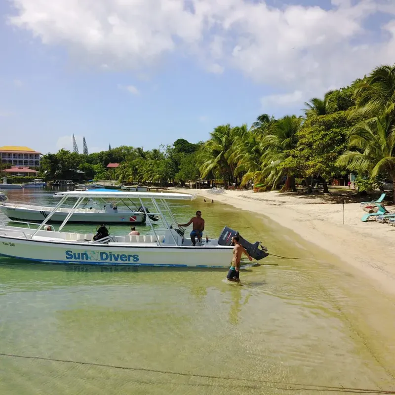 Plage tropicale avec bateau de plongée et personnes marchant dans l'eau