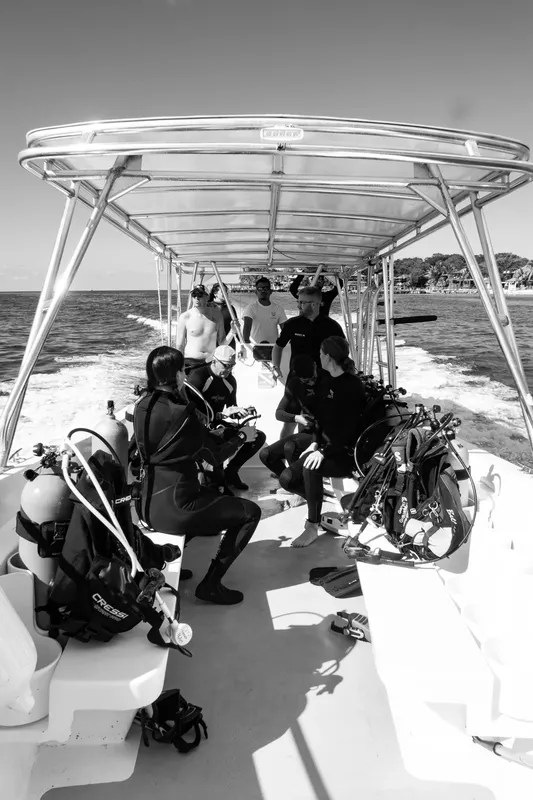 Plongeurs en combinaison sur un bateau, équipement visible, direction mer
