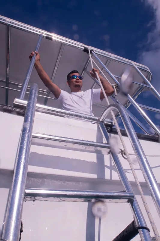 Un homme monte les échelons d'un bateau de plongée sous le soleil