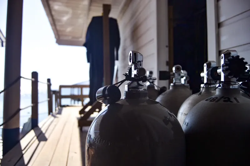 Bouteilles de plongée alignées sur une terrasse en bois ensoleillée