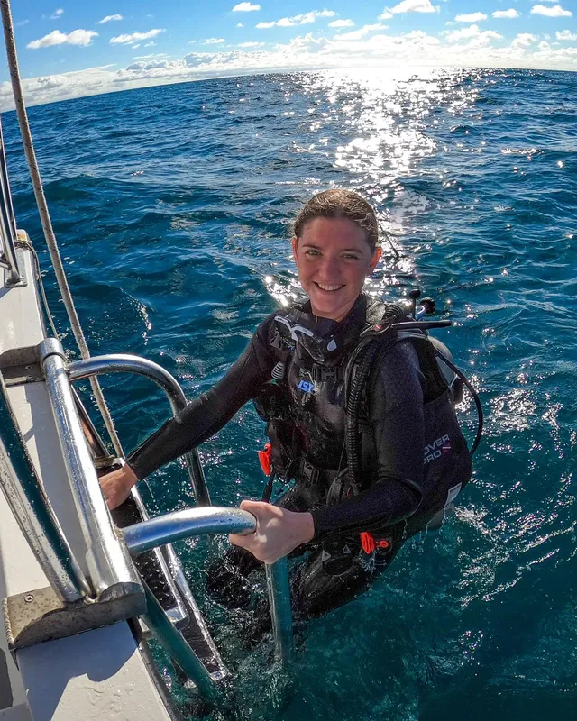 Plongeuse souriante sur un bateau, équipée pour une immersion en mer