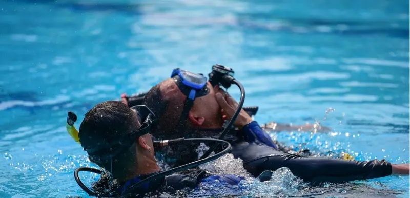 Deux plongeurs s'entraînent en piscine avec leur équipement complet