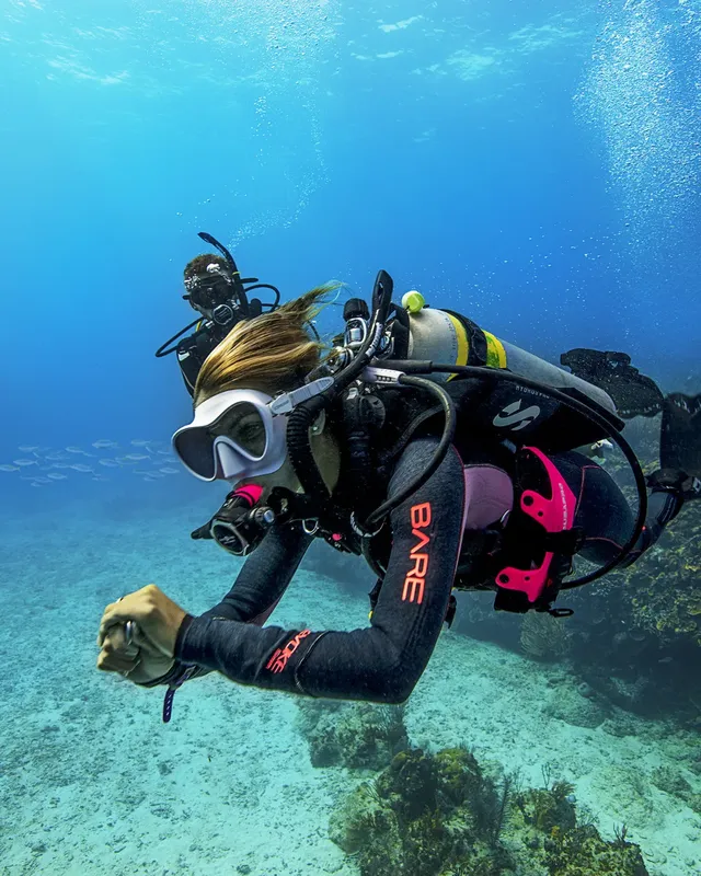 Plongeuse en combinaison explore les fonds marins bleus et clairs
