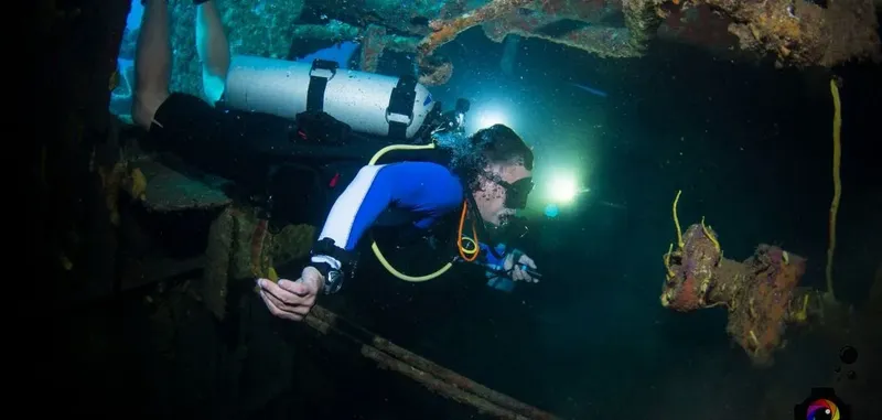 Plongeur explore une épave sombre et rouillée sous l'eau
