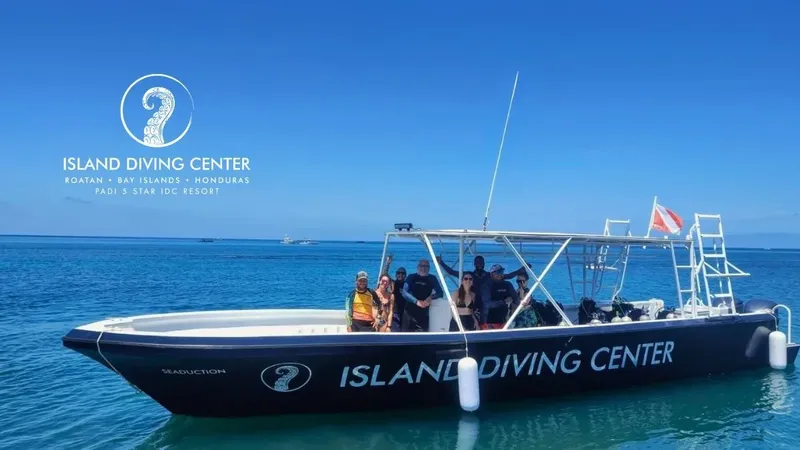 Bateau de plongée noir avec des plongeurs souriants en mer turquoise