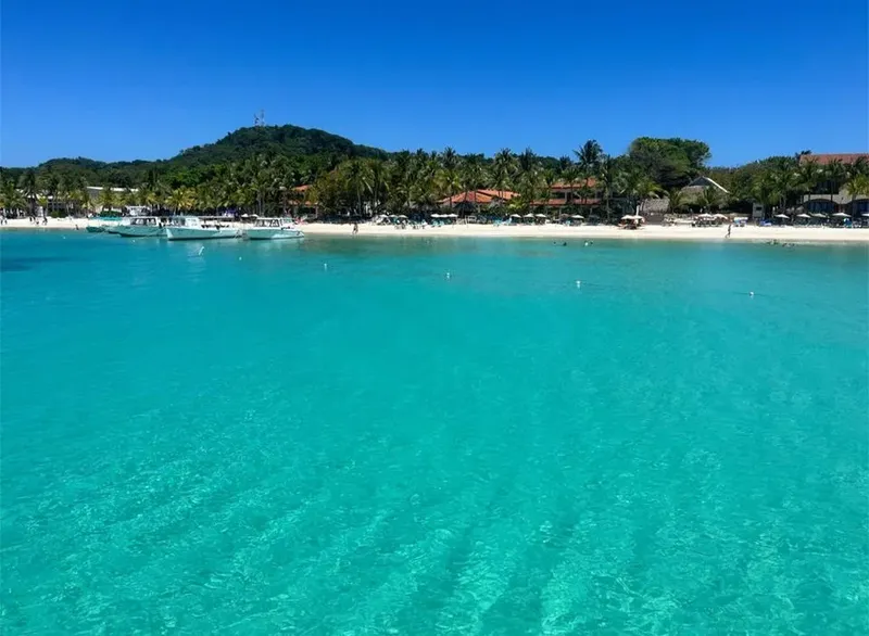 Plage tropicale avec bateaux amarrés et eau turquoise claire