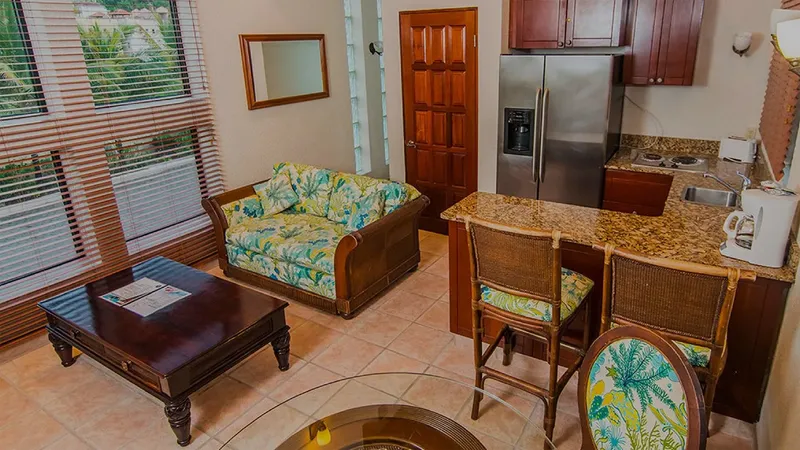Intérieur d'une chambre avec canapé, cuisine équipée et carrelage clair