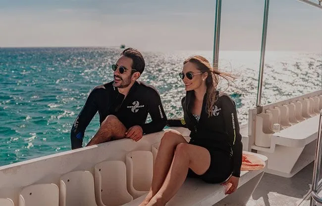 Deux plongeurs souriants sur un bateau en mer, prêts à plonger