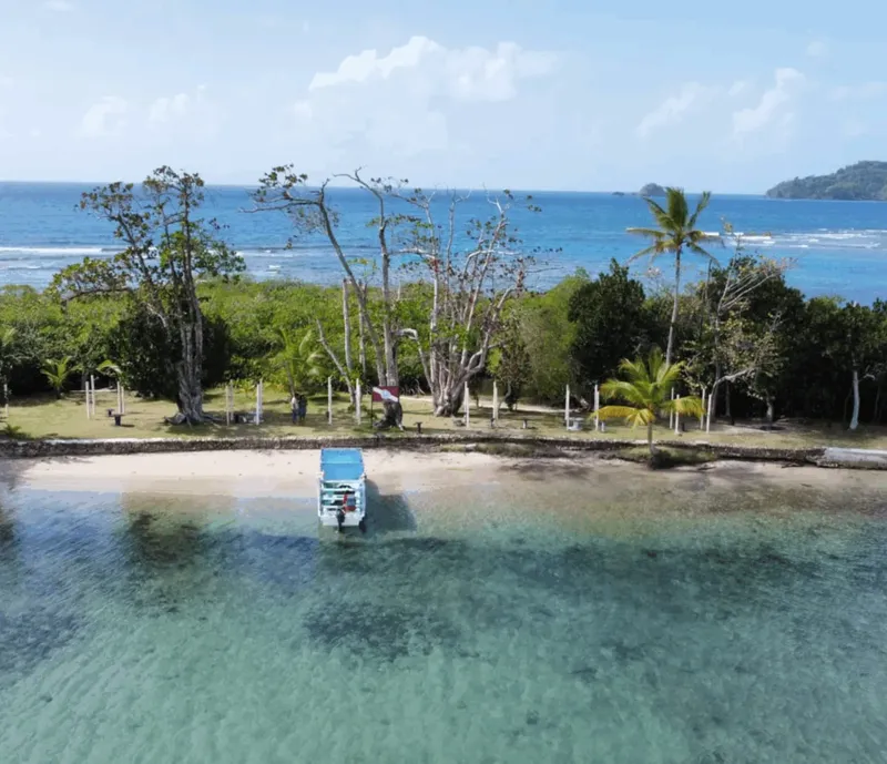 Plage tropicale avec un petit bateau et quelques personnes présentes