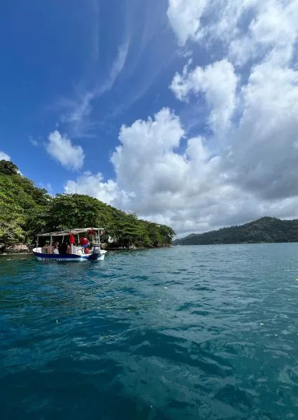 Bateau de plaisance avec passagers naviguant sur une eau turquoise claire