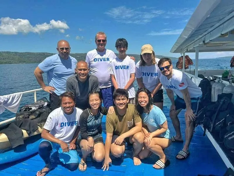 Groupe de plongeurs souriants sur le pont d'un bateau en mer