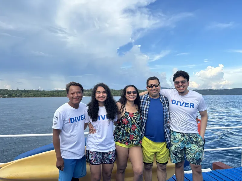 Groupe de cinq personnes souriantes sur un bateau en mer