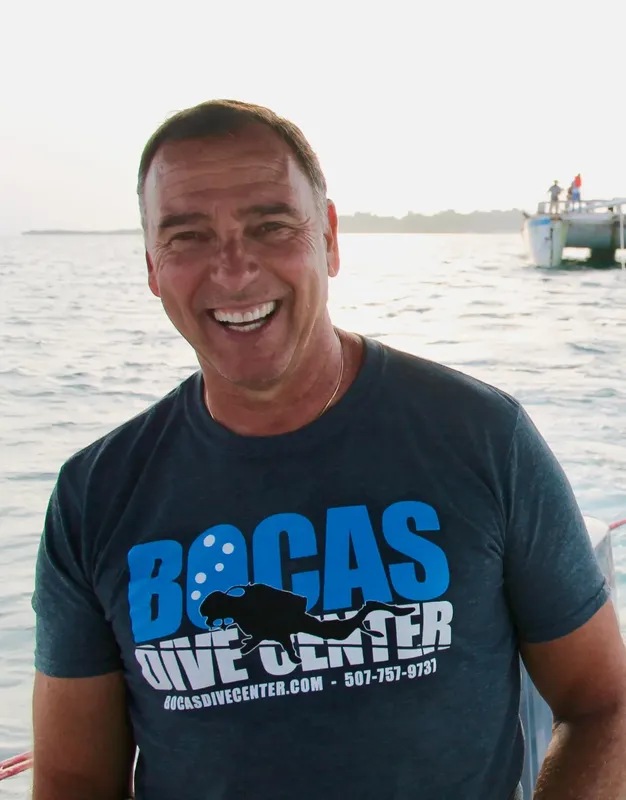 Homme souriant portant un t-shirt avec le logo d'un centre de plongée