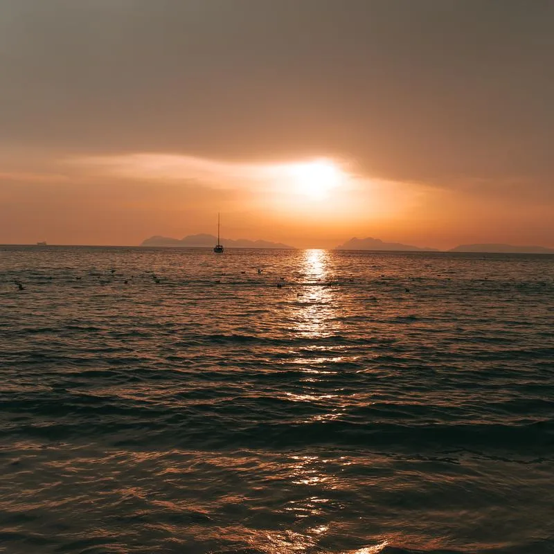 Coucher de soleil sur la mer avec un voilier à l'horizon