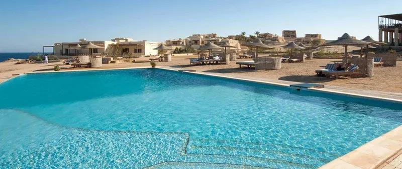 Piscine d'un centre de vacances avec des transats et bâtiments