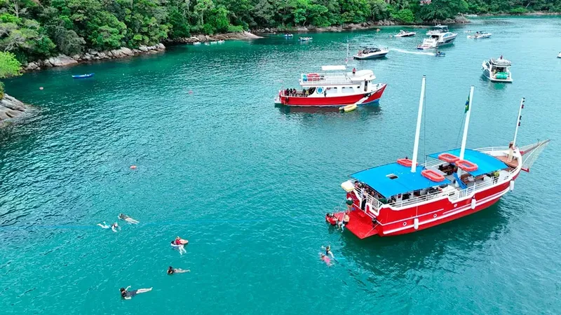 Bateau de plongee amarré dans une baie turquoise avec des nageurs