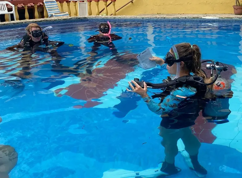 Trois plongeurs en formation dans une piscine, équipement complet visible
