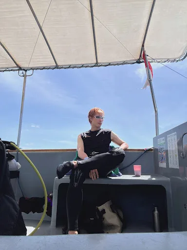 Plongeuse assise sur un bateau avec son équipement complet