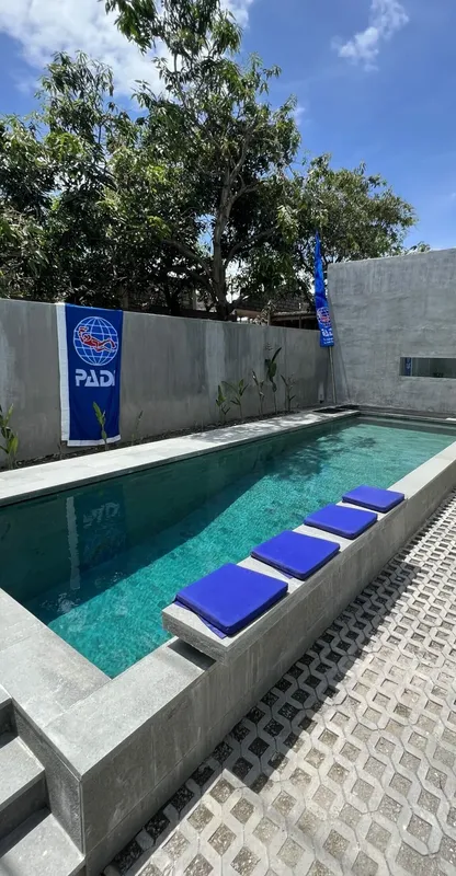 Piscine turquoise avec coussins bleus et drapeaux PADI au fond