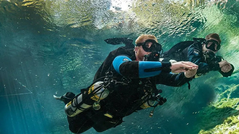 Deux plongeurs en combinaison explorent les fonds marins, communication sous-marine