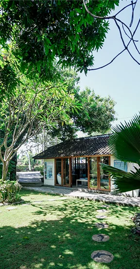 Petite construction avec une facade vitrée entourée de végétation luxuriante