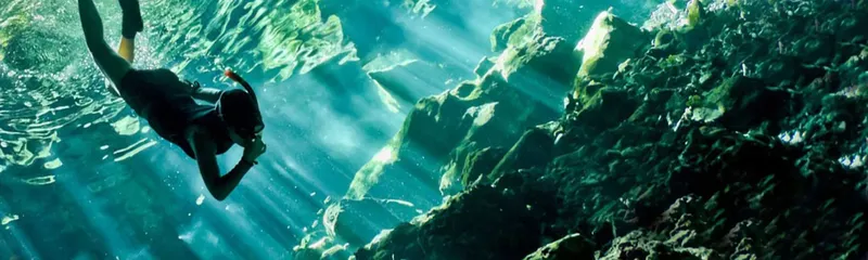 Plongeur explore une grotte sous-marine avec des rayons de lumière