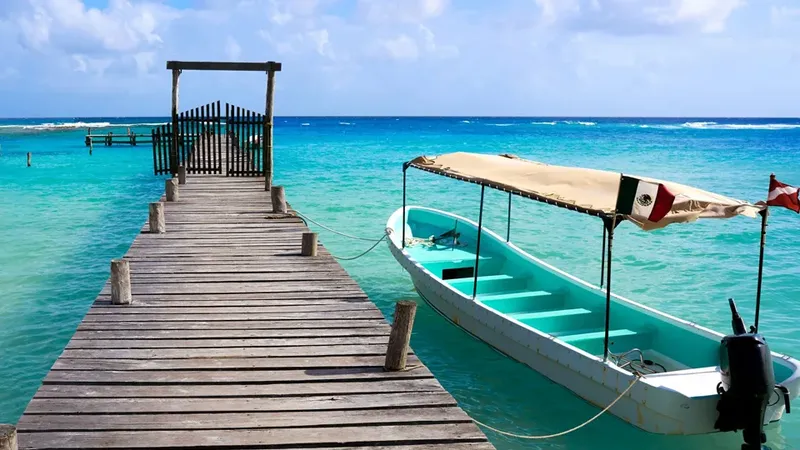 Ponton en bois menant à un bateau turquoise sur mer calme
