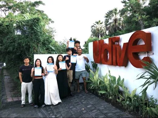 Groupe de personnes souriantes tenant des certificats devant un mur