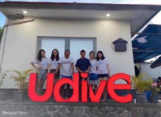 Groupe de personnes souriantes devant une facade et un grand lettrage