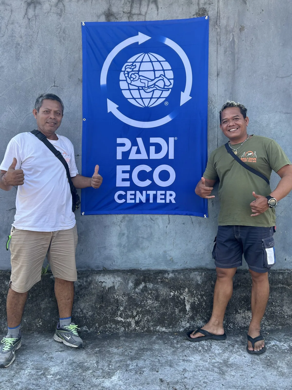 Deux hommes souriants posent devant une bannière PADI Eco Center