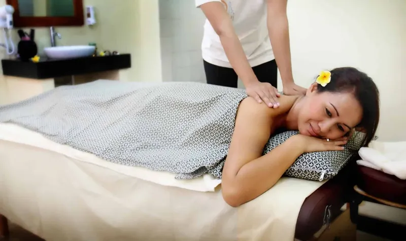 Femme allongée sur une table de massage reçoit un soin relaxant