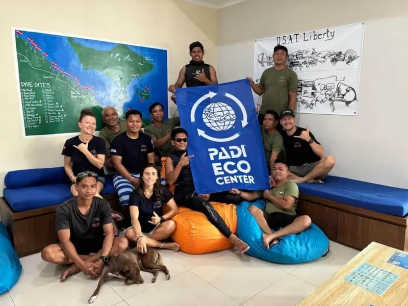 Groupe de personnes souriantes posant devant un logo PADI Eco Center
