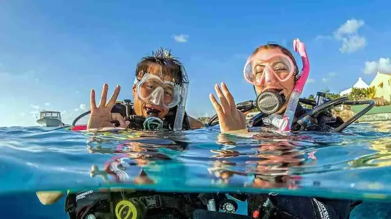 Deux plongeurs souriants, avec masque et détendeur, dans l'eau claire
