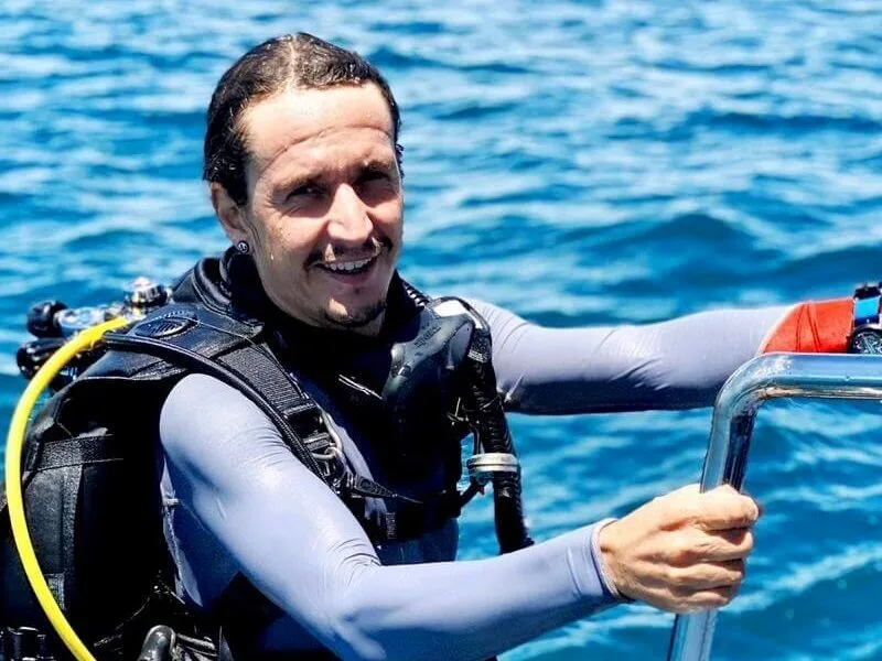 Plongeur souriant équipé d'un gilet et d'une bouteille sur un bateau