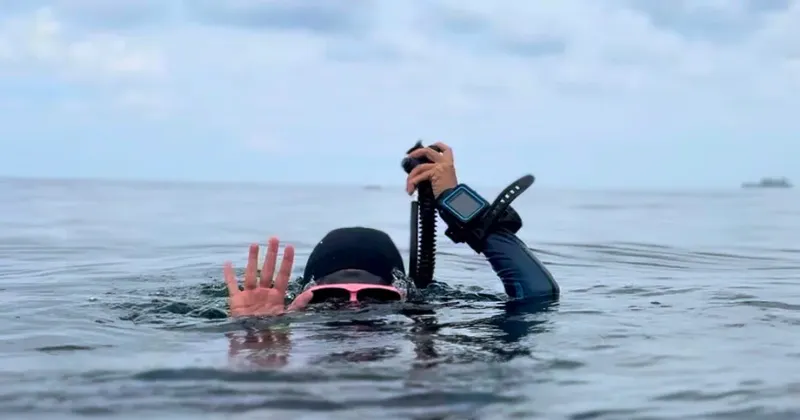 Plongeur en apnée, bras levé, appareil photo sous l'eau
