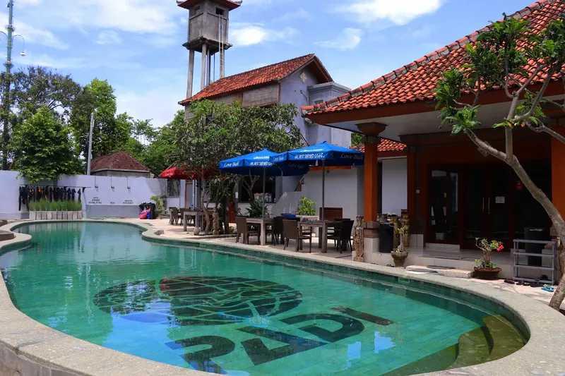 Piscine avec logo PADI au fond, bâtiments et végétation tropicale