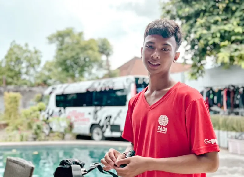 Jeune homme souriant, portant un t-shirt rouge avec un logo