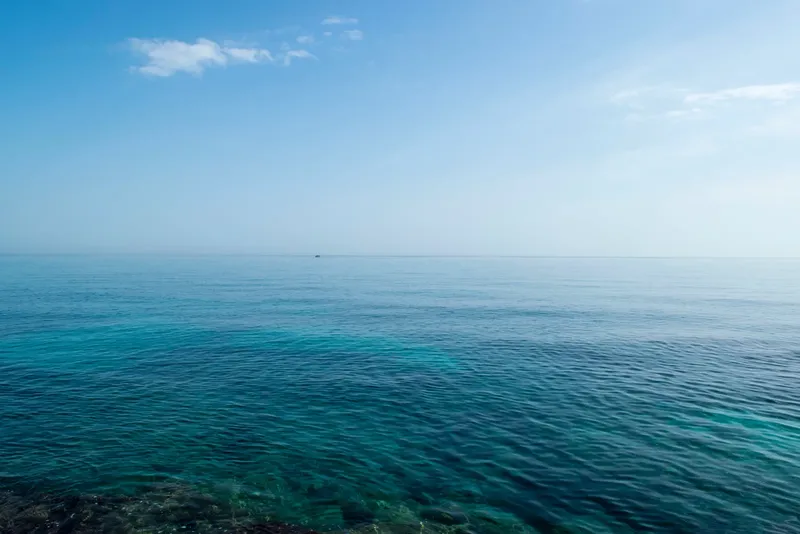 Vue d'une mer bleue calme avec un bateau au loin