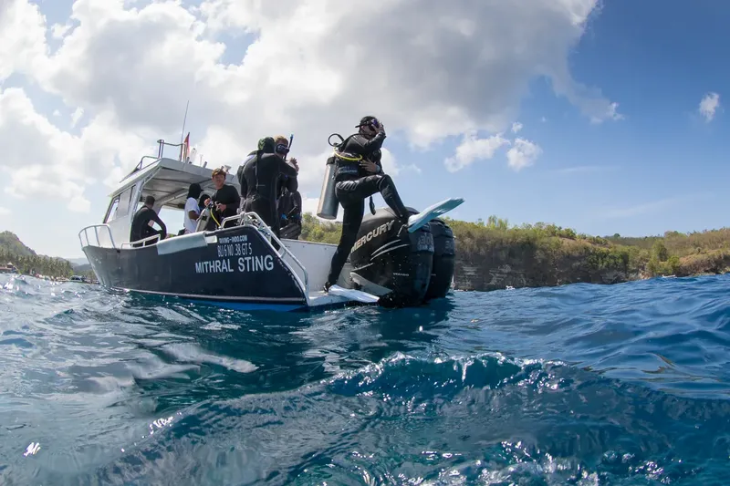Plongeurs s'équipent sur un bateau en mer, ciel bleu et côte