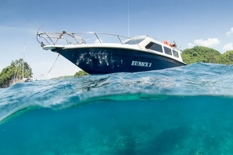 Bateau de plongée bleu et blanc à la surface de l'eau turquoise