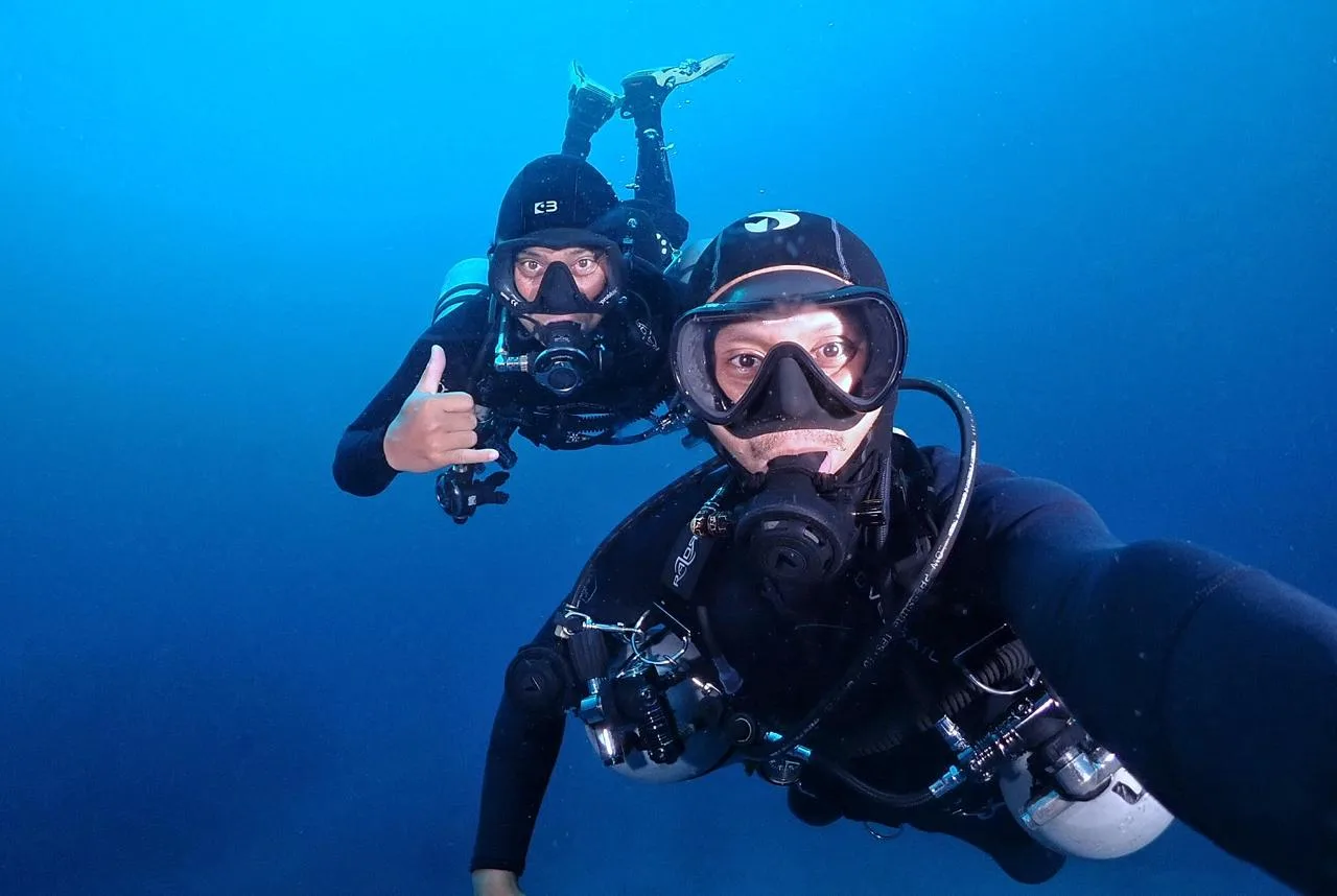 Deux plongeurs souriants font un signe de validation sous l'eau
