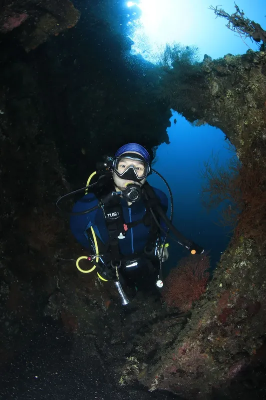 Plongeur en combinaison bleue explore une grotte sous-marine éclairée