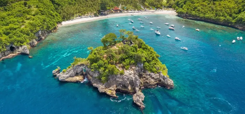 Vue aérienne d'une île rocheuse avec des bateaux dans une baie turquoise